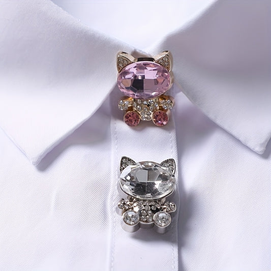 Cat-shaped brooches with pink and clear gemstones on a white shirt.