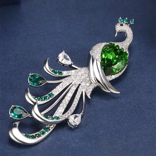 Peacock-shaped brooch with green and clear gemstones on a dark blue background