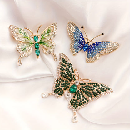 Three butterfly-shaped brooches with gemstones on a white fabric background
