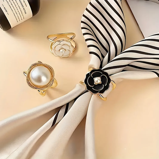 Two pearl-themed napkin rings on a striped black and white napkin with a beige background.