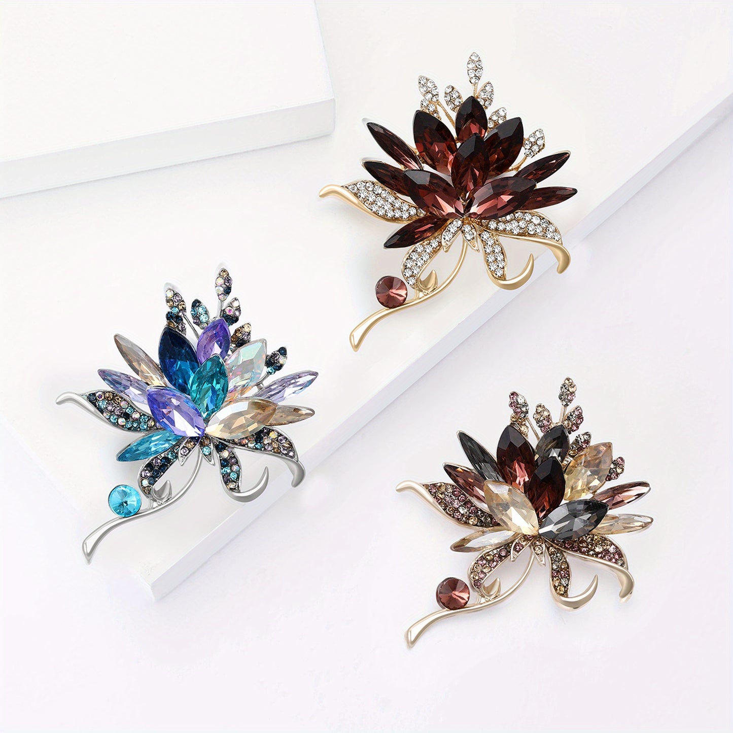 Three decorative brooches with gemstones on a white background