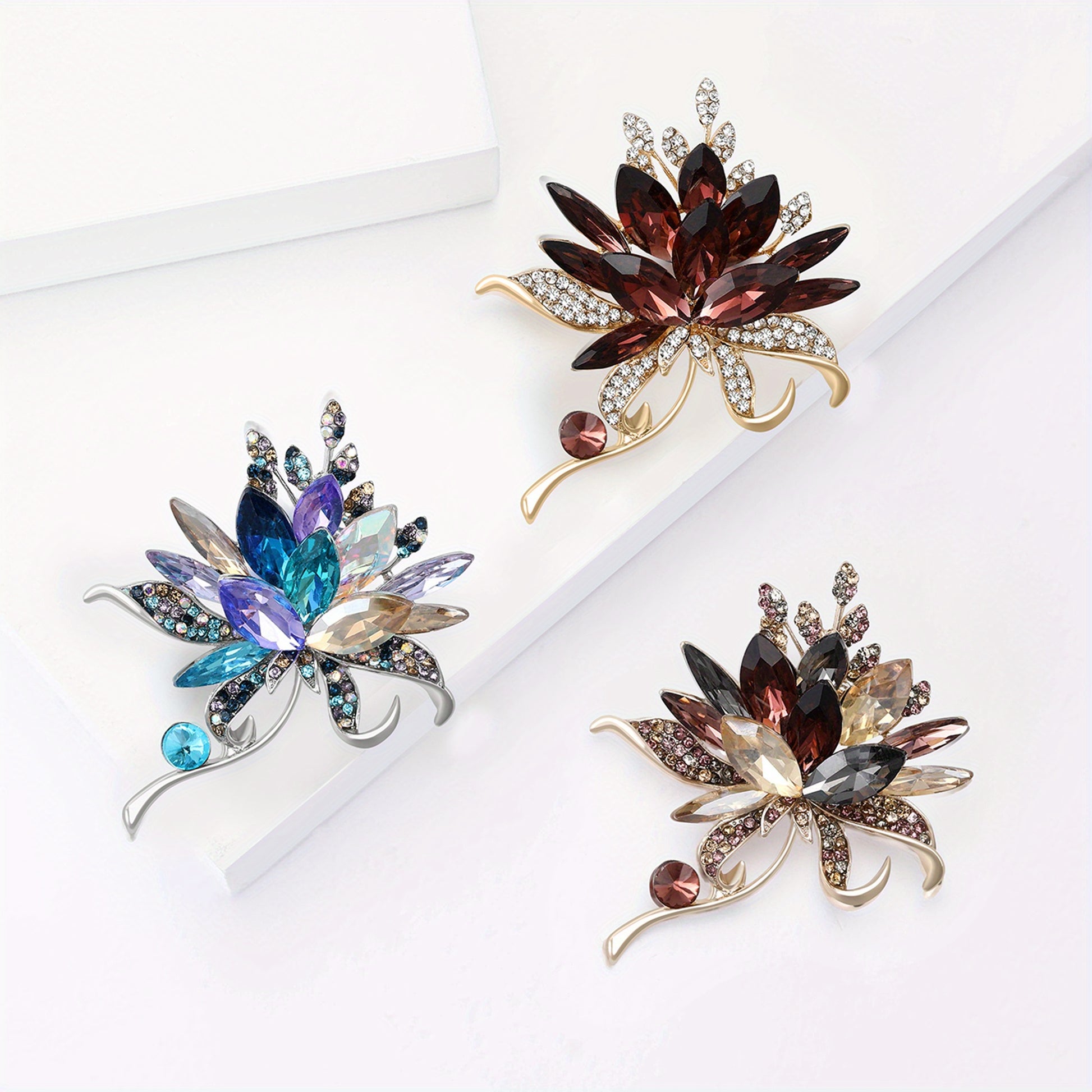 Three decorative brooches with gemstones on a white background