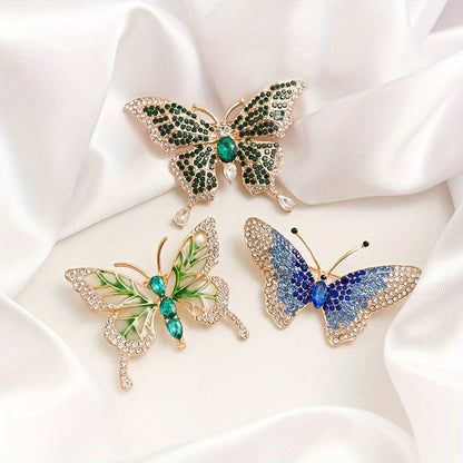 Three butterfly-shaped brooches with gemstones on a white fabric background