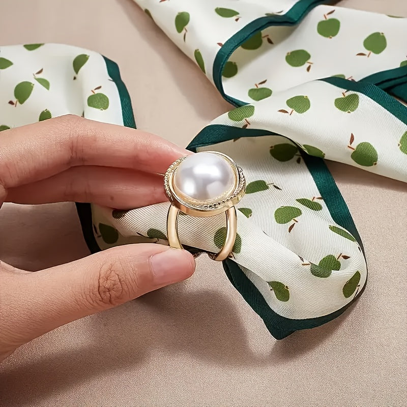 Gold ring with a pearl held over a patterned fabric background