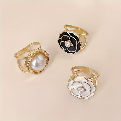 Three gold rings with floral designs and pearls on a beige background