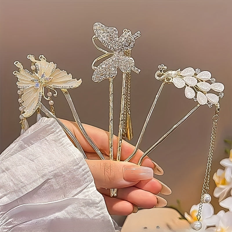 Three decorative hair sticks held by a hand against a neutral background