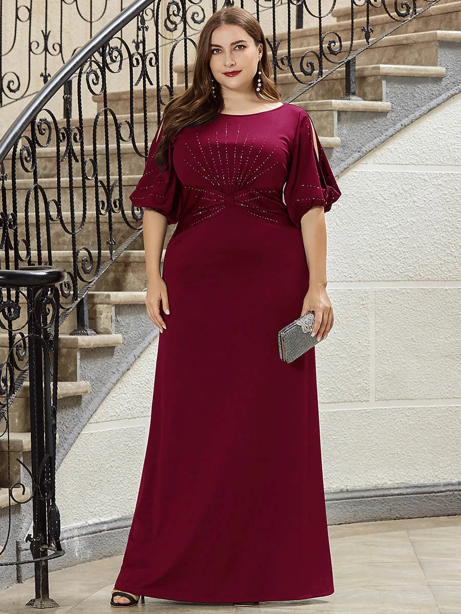 Woman in a burgundy evening gown standing on a staircase.