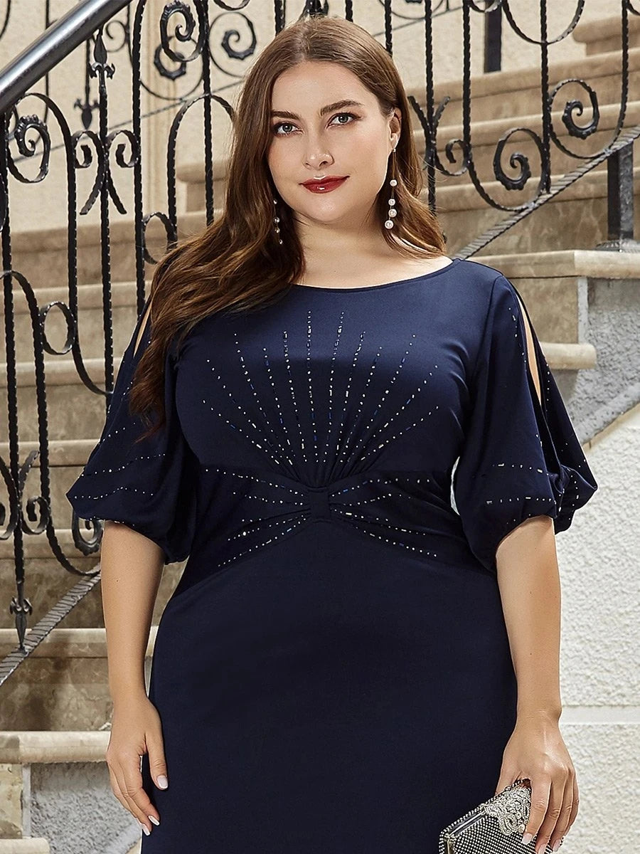 Woman in a navy blue dress with decorative elements standing on steps.