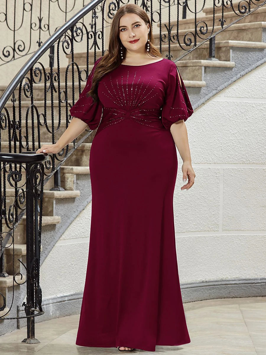 Woman in a burgundy evening gown standing on a staircase.