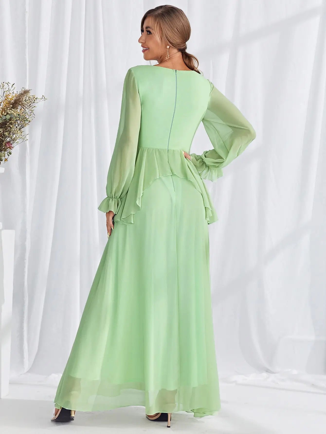 Woman wearing a light green dress with long sleeves against a white background