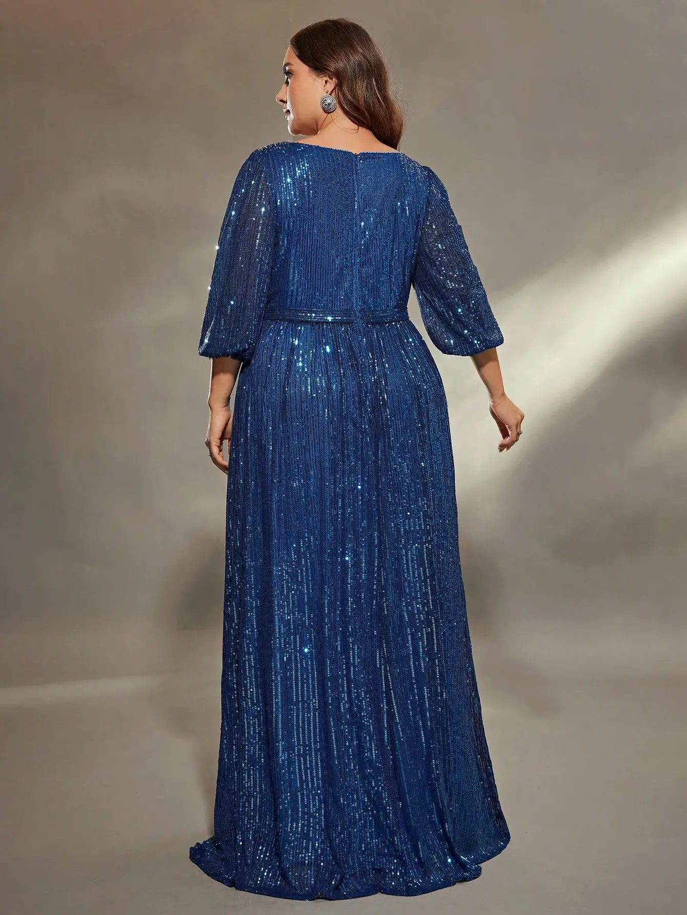 Woman wearing a blue sequin dress against a neutral background