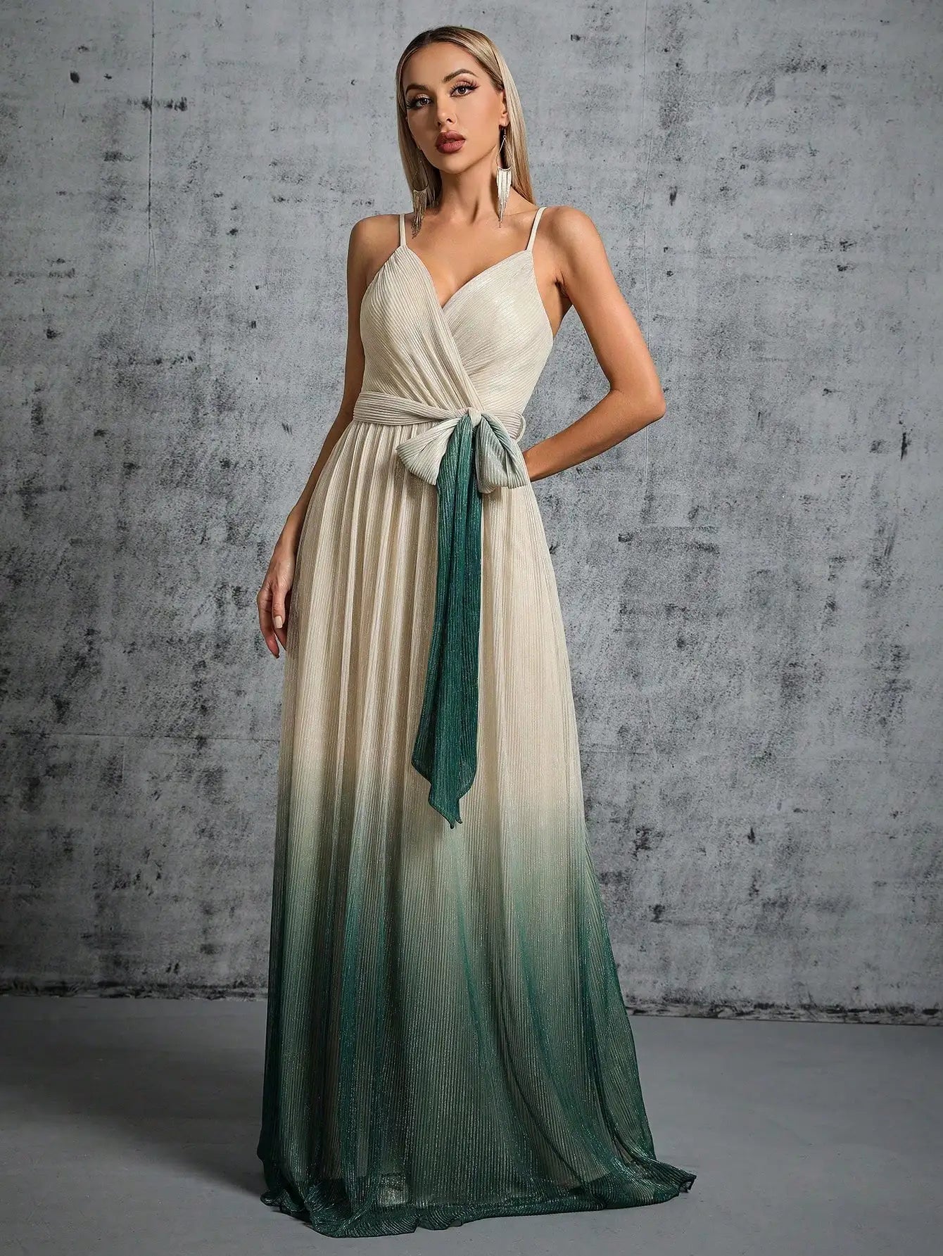 Woman wearing a white and green gradient dress against a gray concrete wall.