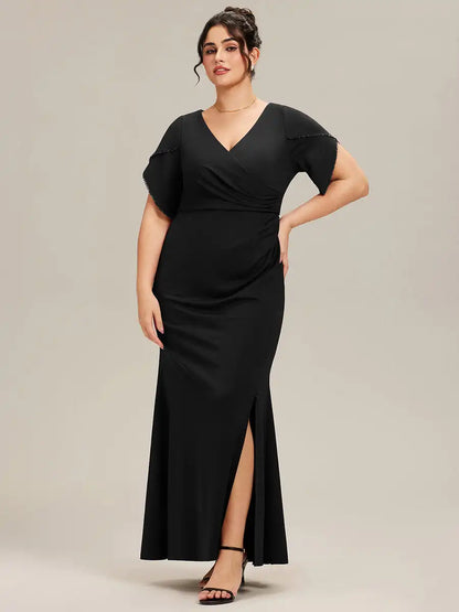 Woman wearing a black dress with a slit on a plain background