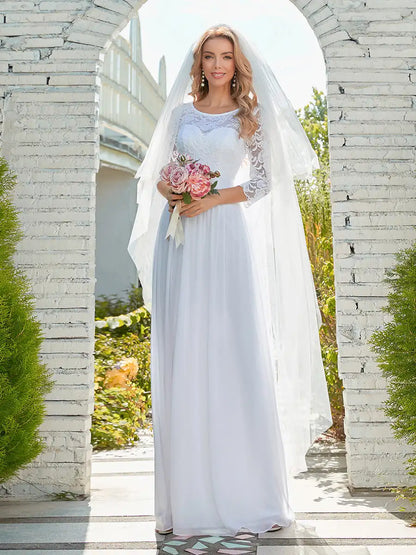 Woman in a white wedding dress holding flowers, standing in front of a stone archway.