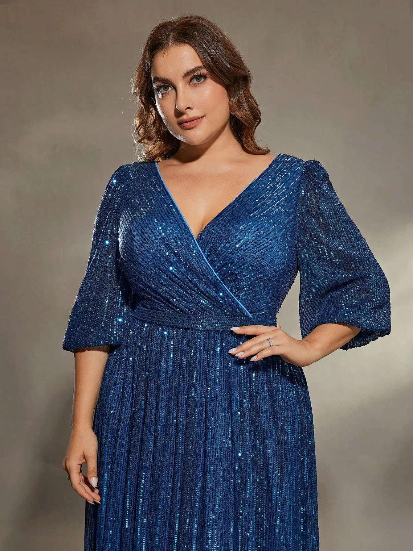 Woman wearing a blue glittery dress against a neutral background