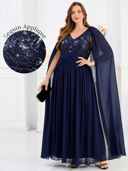 Woman wearing a navy blue evening gown with sequin applique and cape, on a white background.