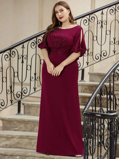 Woman in a burgundy evening gown standing on a staircase with decorative railings.
