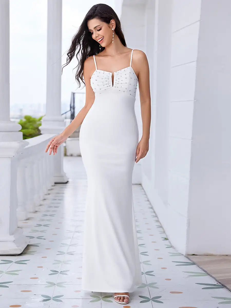 Woman in a white evening gown standing on a decorative floor with columns in the background