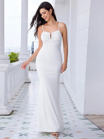 Woman in a white evening gown standing on a decorative floor with columns in the background