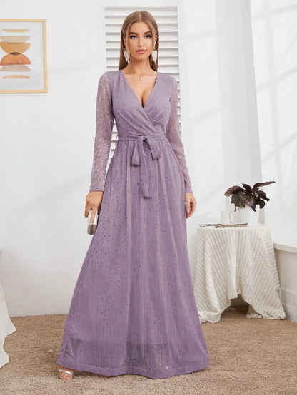 Woman wearing a long purple dress in a room with a table and plant.