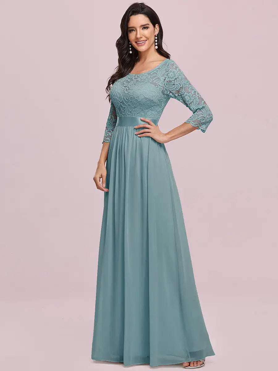 Woman wearing a teal lace dress with a plain background