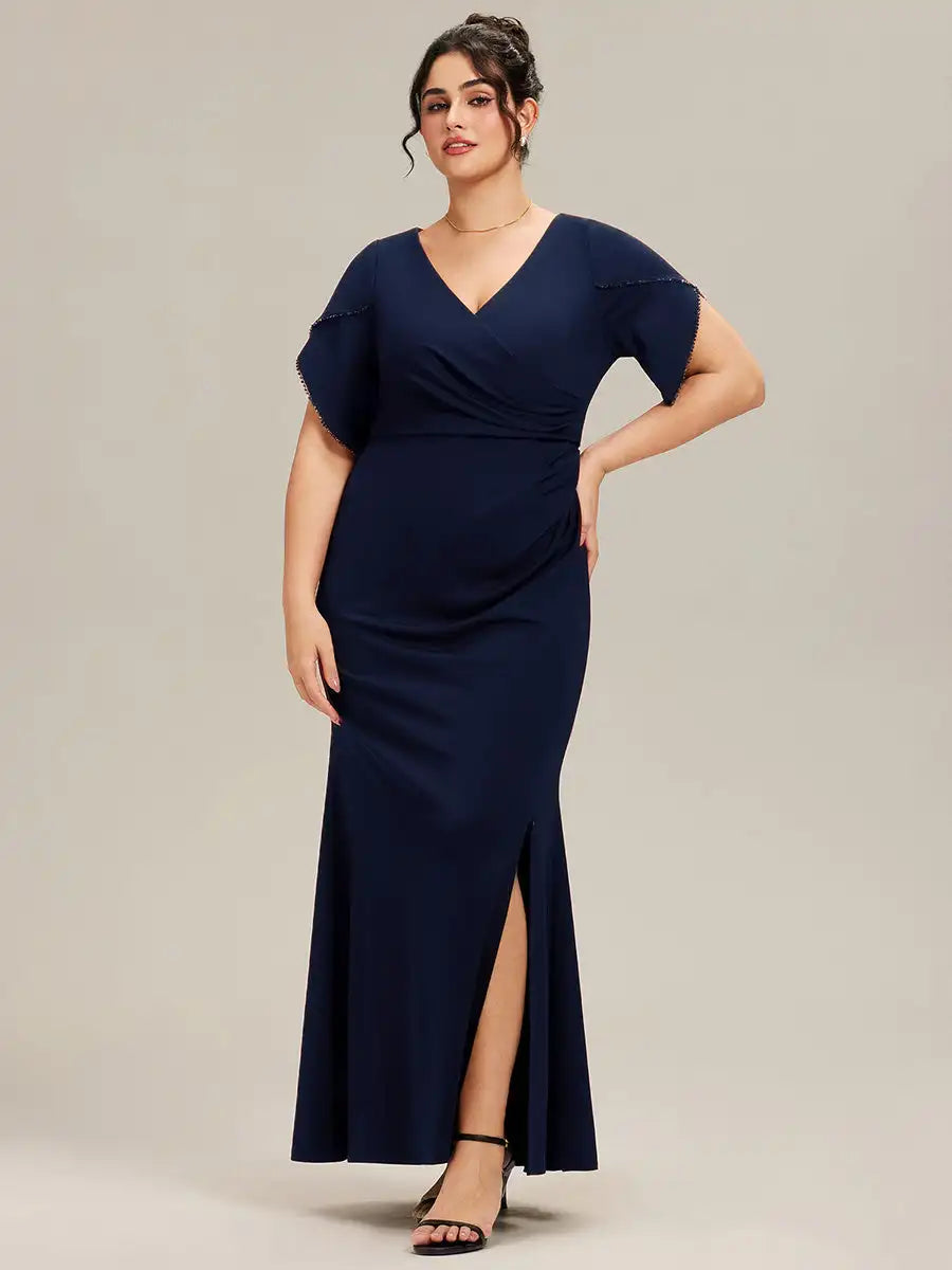 Woman wearing a navy blue dress with a slit on a plain background