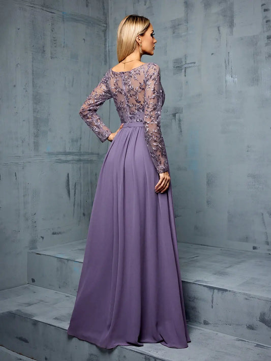 Woman wearing a long purple dress with lace detailing against a gray concrete wall.