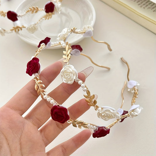Decorative headband with red flowers, pearls, and gold leaves held by a hand on a light background.