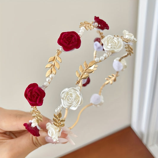 Decorative headband with red and white flowers and gold leaves held by a hand against a neutral background.