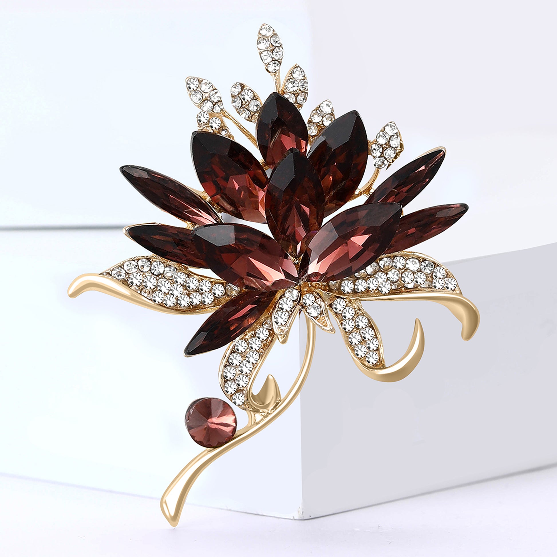 Decorative brooch with red gemstones and gold accents on a white background