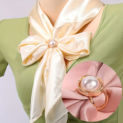 Cream-colored satin bow with pearl center on a green outfit, close-up view.