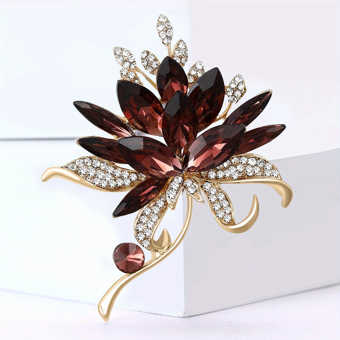 Decorative brooch with red gemstones and gold accents on a white background